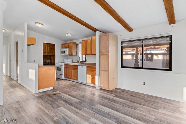 Dining area and Kitchen featuring white appliances, vaulted ceiling with beams, light wood style floors, and a sink | Image 9