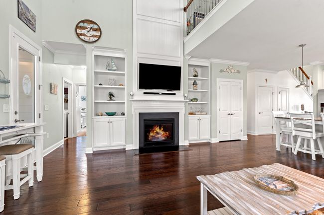 Living room featuring a fireplace with flush hearth, dark wood-type flooring, crown molding, and built in features | Image 14