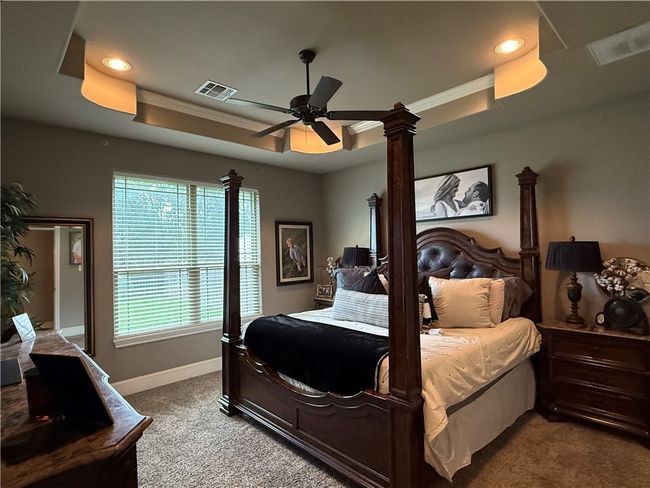 Carpeted bedroom with a raised ceiling, recessed lighting, ornamental molding, and a ceiling fan | Image 12