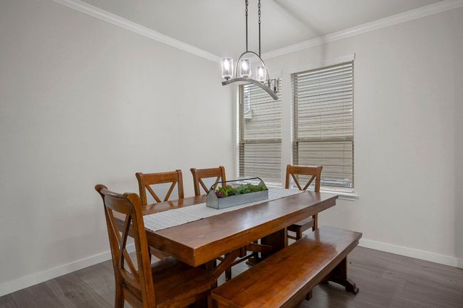 Dining room with dark wood finished floors, baseboards, crown molding, and a chandelier | Image 9