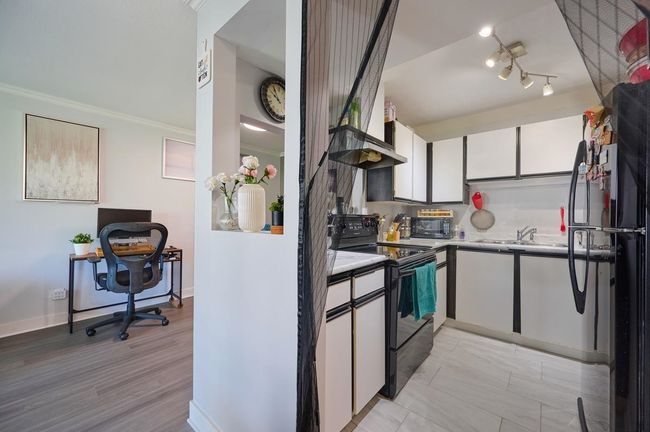 Kitchen featuring light countertops, a sink, white cabinets, baseboards, and black appliances | Image 8