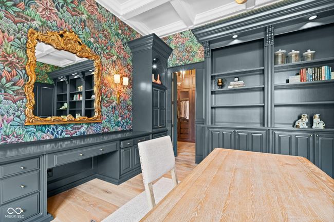office space featuring light wood finished floors, wallpapered walls, built in study area, coffered ceiling, and crown molding | Image 39
