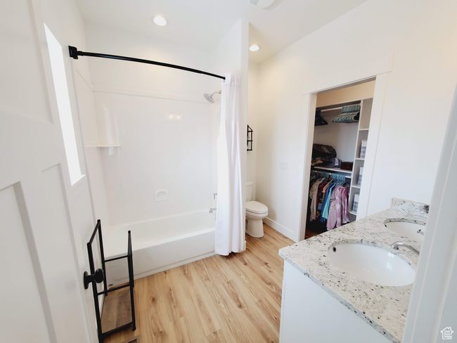 Full bath with wood finished floors, a sink, shower / bath combo with shower curtain, and a walk in closet | Image 21