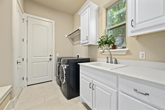 Washroom featuring washing machine and clothes dryer, cabinet space, and light tile flooring | Image 11