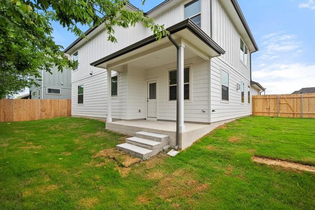 Rear view of house with board and batten siding, a patio area, and a fenced backyard | Image 24