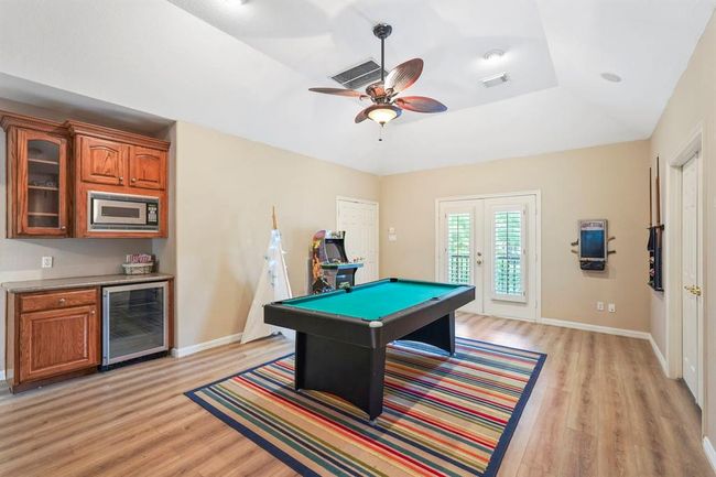 Game room upstairs with a built-in bar area equipped with a microwave and mini-fridge. French doors provide leading you to the balcony. | Image 16