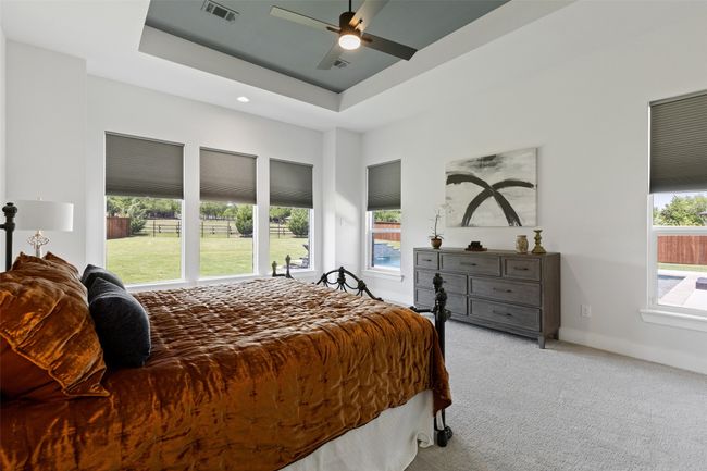 Bedroom featuring visible vents, a raised ceiling, light colored carpet, and multiple windows | Image 17