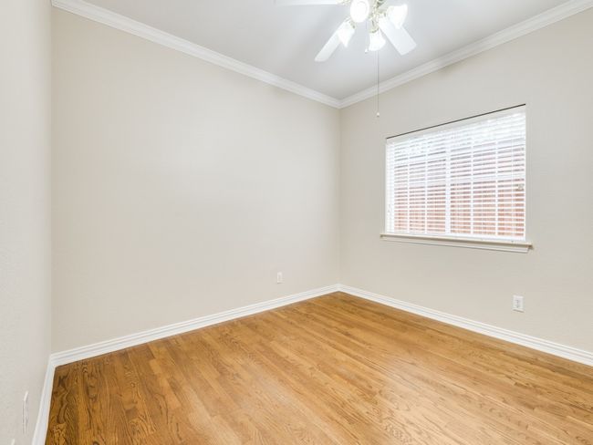 Downstairs bedroom two with hardwood flooring, crown molding, and ceiling fan | Image 19