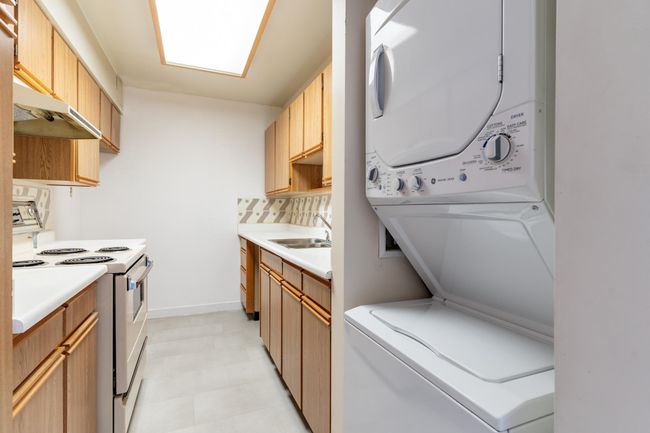 Washroom featuring stacked washer / drying machine, a sink, and laundry area | Image 12