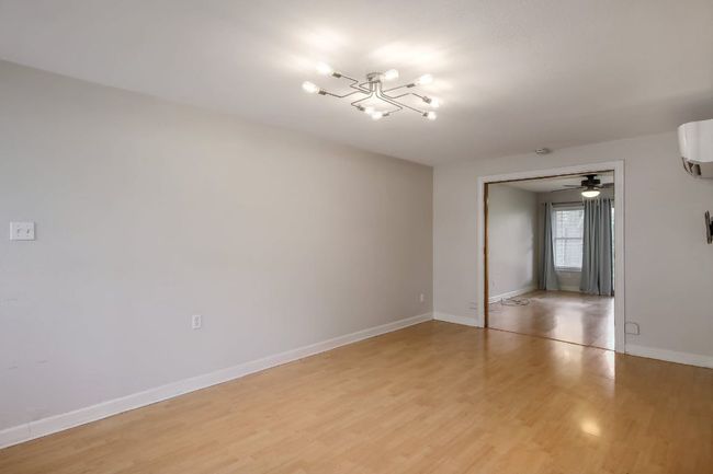 Spare room with a chandelier, light wood-type flooring, baseboards, and a wall mounted air conditioner | Image 22