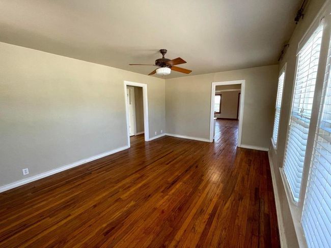 Unfurnished room with dark wood finished floors, ceiling fan, and baseboards | Image 6