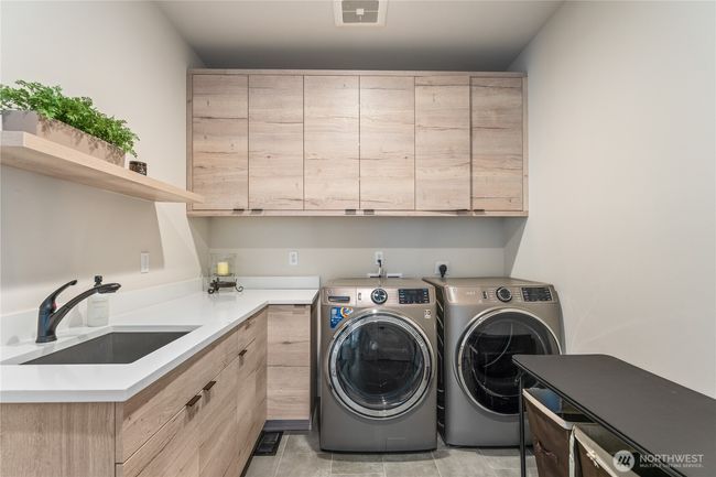 The spacious laundry room and mudroom, conveniently located off the garage, offers abundant cabinetry and counter space for organization, storage, and everyday functionality with a clean, modern design | Image 30
