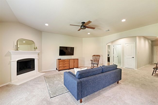 Living area featuring arched walkways, light carpet, ceiling fan, recessed lighting, and a fireplace with raised hearth | Image 9