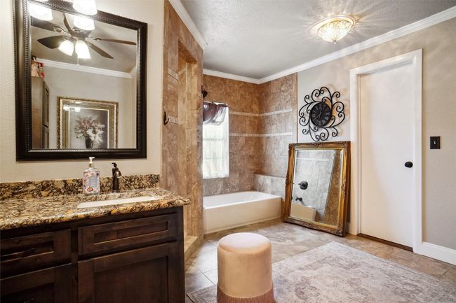 Primary bathroom with a garden tub, vanity, ceiling fan, ornamental molding, and a shower | Image 15