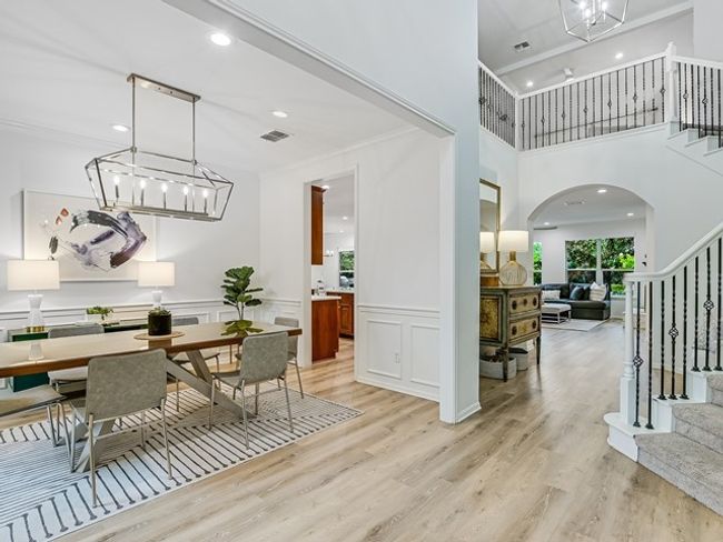 Dining area with visible vents, crown molding, light wood finished floors, stairway, and arched walkways | Image 4