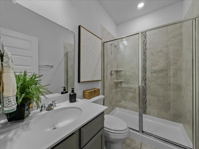 Full bathroom with a stall shower, toilet, vanity, tile patterned floors, and recessed lighting | Image 19