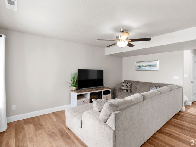 Living room featuring baseboards, visible vents, a ceiling fan, and light wood-style flooring | Image 4