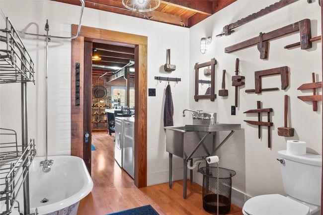Full bath with toilet, wood finished floors, washer / dryer, a freestanding tub, and beamed ceiling | Image 19