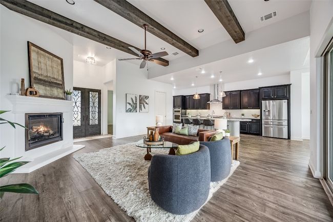 Living room with wood finished floors, a ceiling fan, a glass covered fireplace, beam ceiling, and recessed lighting | Image 4