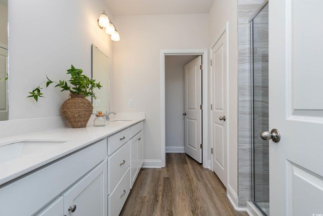 Bathroom featuring wood finished floors, tiled shower, and double vanity | Image 25