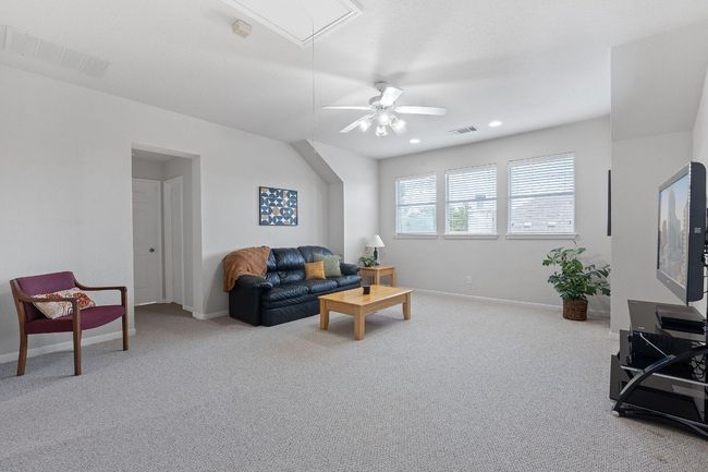 Carpeted living area featuring attic access, a ceiling fan, baseboards, and recessed lighting | Image 16