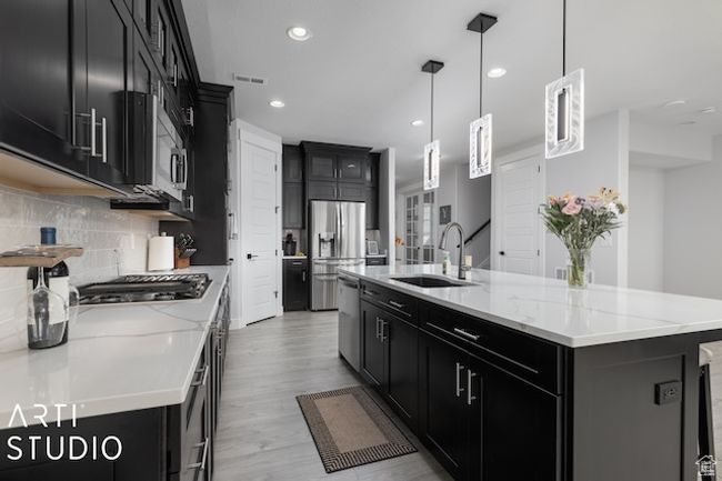 Kitchen featuring a sink, stainless steel appliances, dark cabinetry, and decorative backsplash | Image 12