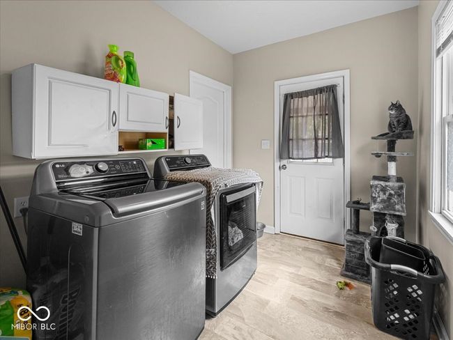 laundry room featuring cabinet space, washer and dryer, healthy amount of natural light, and light wood-style flooring | Image 23