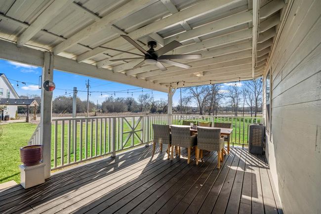 A covered porch off the main home provides the perfect spot to dine outdoors, relax, and take in views of the surrounding property. | Image 24