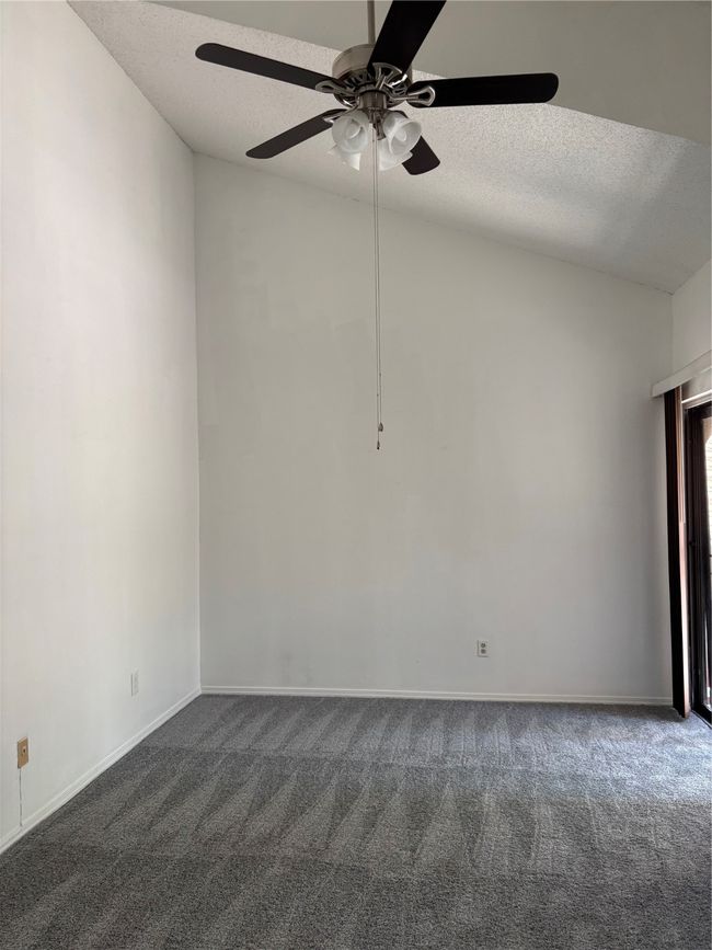 Unfurnished room with a ceiling fan, baseboards, dark carpet, and a textured ceiling | Image 13
