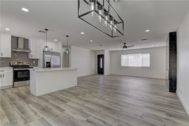 Kitchen featuring appliances with stainless steel finishes, wall chimney exhaust hood, recessed lighting, white cabinetry, and a center island | Image 17