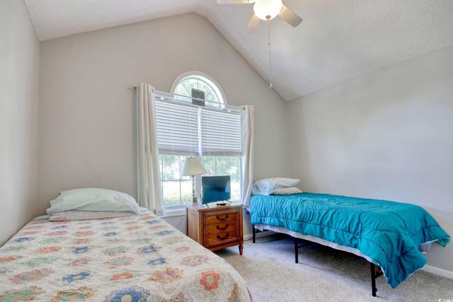 Carpeted bedroom with vaulted ceiling, a ceiling fan, and a textured ceiling | Image 25