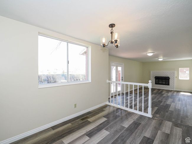 Unfurnished room featuring a chandelier, wood finished floors, and a fireplace | Image 29