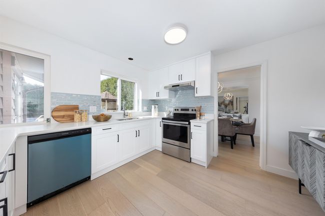 Kitchen featuring light countertops, light wood-type flooring, stainless steel electric range oven, a sink, and dishwasher | Image 10