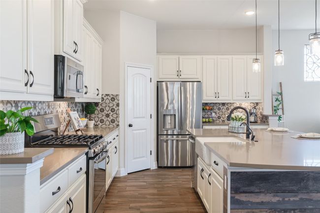 Kitchen featuring dark wood-style flooring, white cabinets, stainless steel appliances and pendant lighting | Image 14