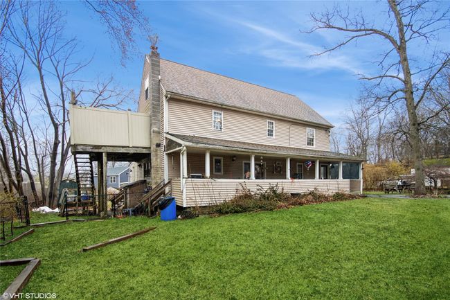 Rear view of house with stairs, roof with shingles, a yard, and a chimney | Image 20