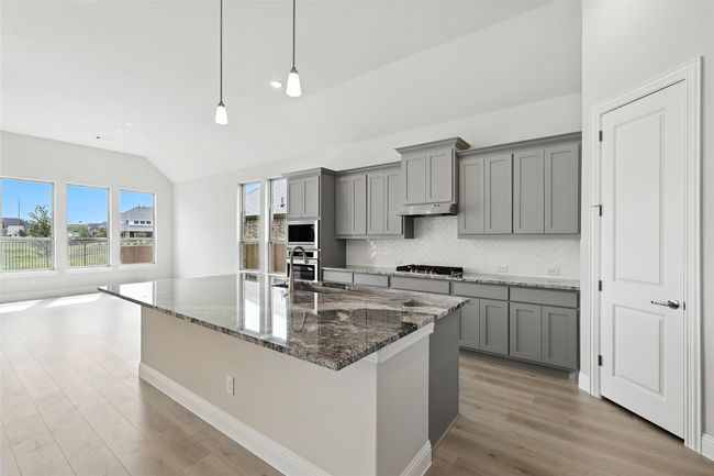Kitchen with gray cabinets, lofted ceiling, decorative backsplash, appliances with stainless steel finishes, and light wood finished floors | Image 7