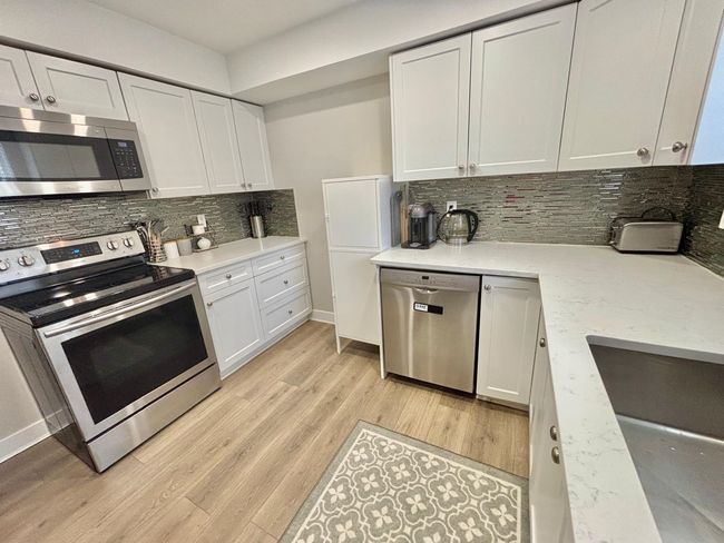 Kitchen featuring stainless steel appliances, backsplash, and white cabinets | Image 9