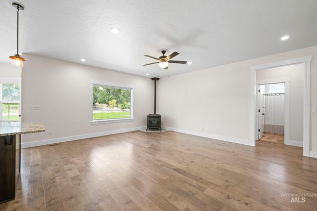 Unfurnished living room with a wood stove, ceiling fan, plenty of natural light, light wood-style floors, and recessed lighting | Image 14