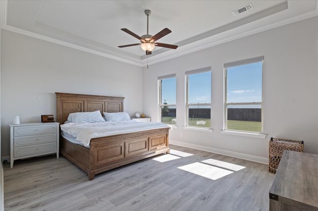 Bedroom with a raised ceiling, light wood finished floors, ornamental molding, and ceiling fan | Image 19