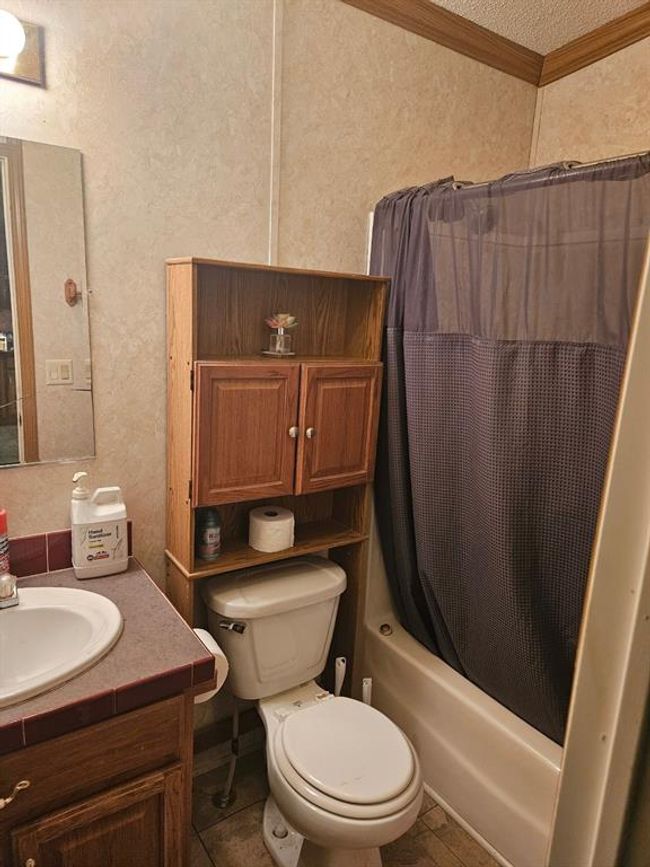 Full bathroom with shower / bath combo with shower curtain, crown molding, tile patterned floors, toilet, and vanity | Image 38