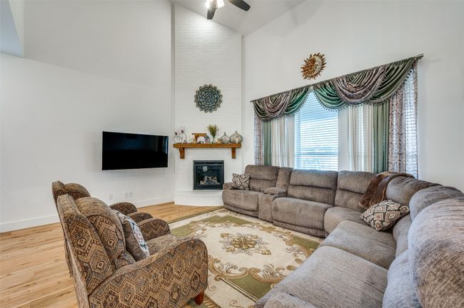 Living room with high vaulted ceiling, wood finished floors, ceiling fan, and a large fireplace | Image 4