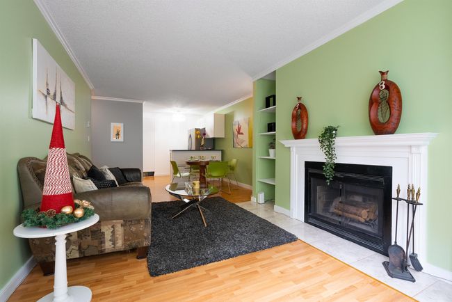 Living area featuring baseboards, wood finished floors, a fireplace with flush hearth, and crown molding | Image 4