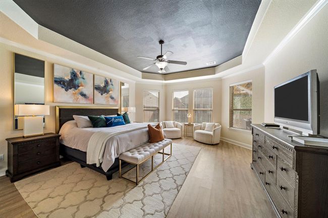 The primary bedroom exudes tranquility with its spacious layout, sitting area, and large windows ushering in natural light. This inviting retreat features an expansive walk-in closet and a private ensuite bath, offering dual vanities, a soaking tub, and a glass-enclosed shower for ultimate relaxation. | Image 4