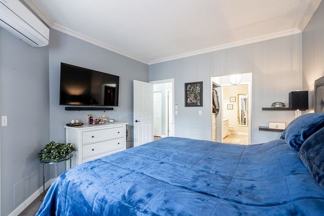 Bedroom with ensuite bath, a wall unit AC, crown molding, and baseboards | Image 16