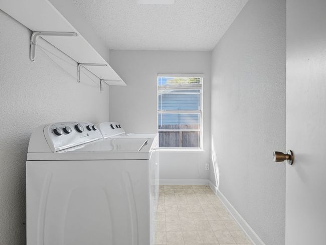 Laundry room with a textured wall, a textured ceiling, and washing machine and clothes dryer | Image 20