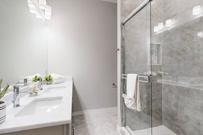 Full bathroom with double vanity, a stall shower, and baseboards | Image 11