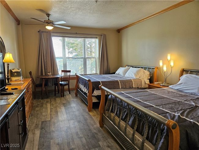 Bedroom with dark wood-style floors, ornamental molding, and a textured ceiling | Image 5