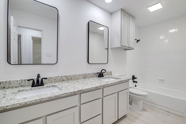 Full bathroom with toilet, double vanity, and bathing tub / shower combination | Image 32