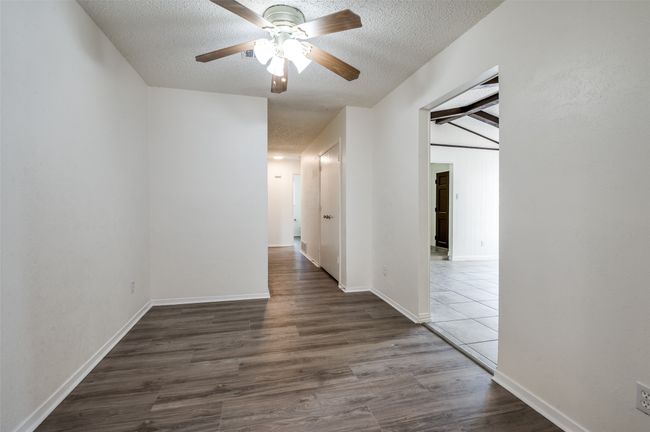 Hallway with a textured ceiling and wood finished floors | Image 6