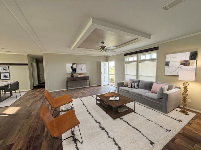 Living area featuring a raised ceiling, wood finished floors, a ceiling fan, and ornamental molding | Image 6